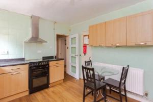 a kitchen with wooden cabinets and a table with chairs at Homely 3 Bedroom House with a Garden in London