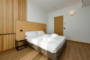 a bedroom with a large white bed with a wooden headboard at Hotel Mauro in Sirmione