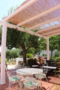 un patio con mesa y sillas bajo una pérgola en Trullo Il Melograno, en Ostuni