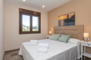 una camera da letto con un grande letto bianco e due finestre di Hacienda El Esteiro - Villas vacacionales a Tapia de Casariego