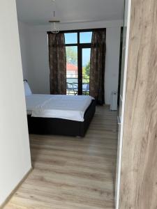 um quarto com uma cama e piso em madeira em A L L E G R I A em Vama Veche