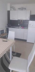 a kitchen with white cabinets and a table and chairs at Апартамент Лана in Byala