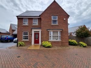 a red brick house with a red door at Deluxe room in a spacious house in Kirby Muxloe
