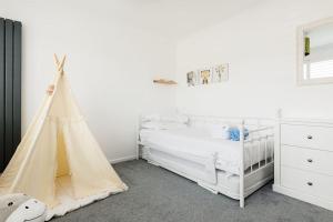 a white bedroom with a bed and a crib at Lulworth House in Poole