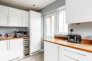 a white kitchen with white cabinets and a toaster oven at Lulworth House in Poole