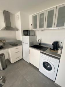 eine weiße Küche mit Waschmaschine in der Unterkunft APPARTEMENT TYPE 2 NEUF +GRANDE TERRASSE in Le Lavandou
