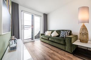 sala de estar con sofá verde y ventana en 200 qm schwimmendes Penthouse en Vieregge