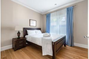 a bedroom with a bed and a window with blue curtains at Vancouver Haven: Luxurious 5-Bedroom Retreat in Vancouver