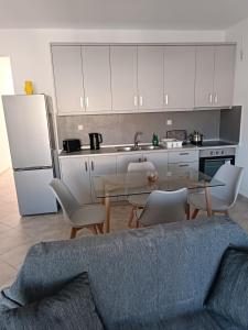 カルパトスにあるEvans apartmentのキッチン(テーブル、椅子付)、キッチン(白いキャビネット付)