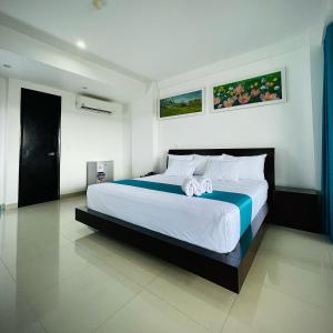 een slaapkamer met een groot bed met witte lakens bij RBB BRITO HOTEL in Tarapoto