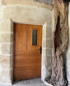 eine Holztür in einem Steingebäude mit einem Baum in der Unterkunft La Chatelleraie in Saint-Étienne-de-Maurs