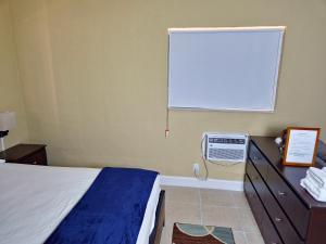a bedroom with a bed and a window with a air conditioner at The Vacay Inn in Lauderdale Lakes