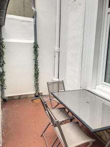 a glass table and two chairs on a porch at Street Home in Boulogne-sur-Mer