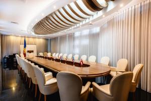 uma sala de conferências com uma mesa longa e cadeiras brancas em President Resort Hotel em Chisinau