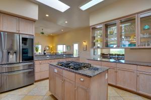 a large kitchen with wooden cabinets and stainless steel appliances at Updated Tucson Home with Panoramic Mtn Views and Pool! in Tucson
