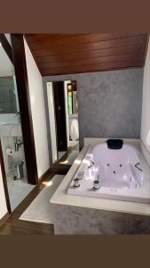 uma banheira branca num quarto com casa de banho em Jardim Secreto - Itaipava em Itaipava