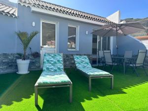a patio with two chairs and an umbrella on the grass at amplio duplex in Tamaimo