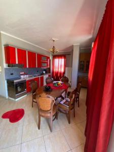 uma cozinha com mesa, cadeiras e armários vermelhos em StartApart City Center em Durrës