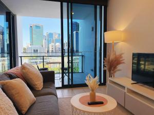 Una sala de estar con un sofá y una ventana grande. en Brisbane Skyline View 2Beds River view Apt, en Brisbane