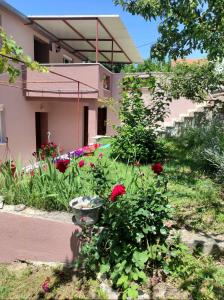 einen Garten vor einem Haus mit roten Rosen in der Unterkunft Apartman Neva in Sinj