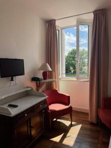 a room with a tv and a chair and a window at La Chatelleraie in Saint-Étienne-de-Maurs