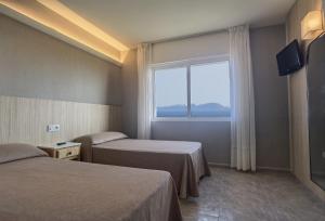 AiosにあるPensión Residencia Ceciliaのベッド2台と窓が備わるホテルルームです。