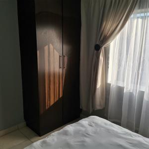 Pablo and Sons Apartments في بولوكوان: غرفة نوم بسرير وخزانة ونافذة
