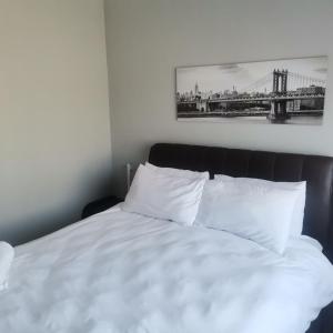 a bedroom with a bed with white sheets and a bridge at Pablo and Sons Apartments in Polokwane