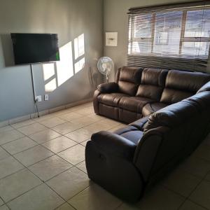 a living room with a couch and a flat screen tv at Pablo and Sons Apartments in Polokwane