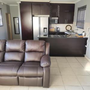 a living room with a couch and a kitchen at Pablo and Sons Apartments in Polokwane