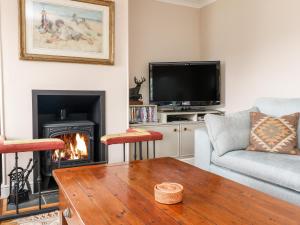 sala de estar con chimenea y TV en Fearnach Bay House en Oban