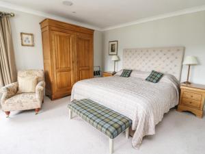 una camera con un grande letto e una sedia di Fearnach Bay House a Oban