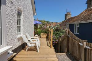 a wooden deck with white chairs on a house at Waverley in Lyme Regis