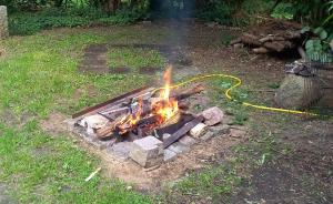 a fire pit in a yard with a yellow hose at Einfachlosmachen-Zeltpunkt 