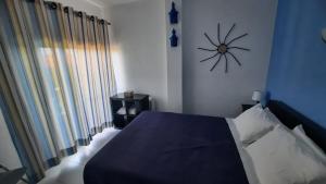 a bedroom with a bed with a clock on the wall at Nora Velha T0+1 em Tavira in Tavira