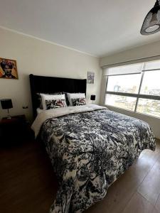 a bedroom with a bed with a black and white blanket at Home Cavero, Moderno y completo departamento in Lima