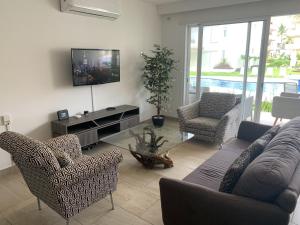 a living room with a couch and chairs and a tv at Acapulco Diamante Varadero D001 in Acapulco