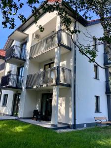 a white building with balconies and a lawn at morze i plaża in Łeba