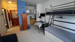 a bedroom with a bunk bed and a kitchen at Nora Velha T0+1 em Tavira in Tavira