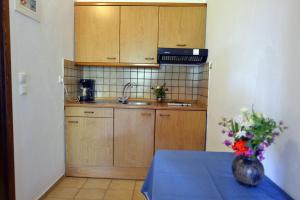 a kitchen with wooden cabinets and a table with a vase of flowers at Haus Katerina in Vourvourou
