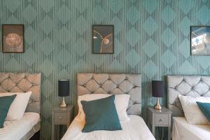 two beds in a bedroom with green wallpaper at 10% discount on long stays in Chigwell