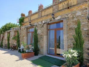 a stone building with glass doors and a patio at Appartamento Olivo in Collecorvino