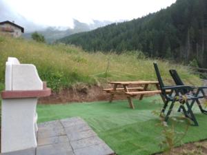 a wooden picnic table and chairs on a green field at monolocale CRIS in Madesimo