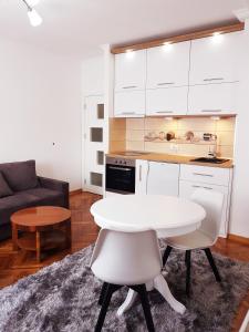 ein Wohnzimmer mit einem weißen Tisch und eine Küche in der Unterkunft Emili apartment in Belgrad