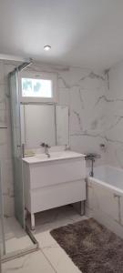 een badkamer met een wastafel, een spiegel en een bad bij villa de campagne à 15 minutes de la mer in LʼÉglise
