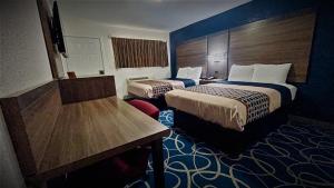 a hotel room with two beds and a desk at Budget Inn Pecos in Pecos