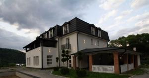 een groot wit huis met een zwart dak bij Berghaus Bucovina in Câmpulung Moldovenesc