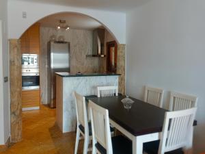 uma cozinha com uma mesa preta e cadeiras brancas em Rentaly Holidays Playa Villaricos em Cuevas del Almanzora