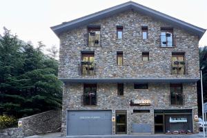 un gran edificio de piedra con ventanas y garaje en Apartaments Turistics El Buner, en Ordino