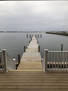 un muelle de madera en medio de una masa de agua en Mariners Cove cottage, en Norfolk